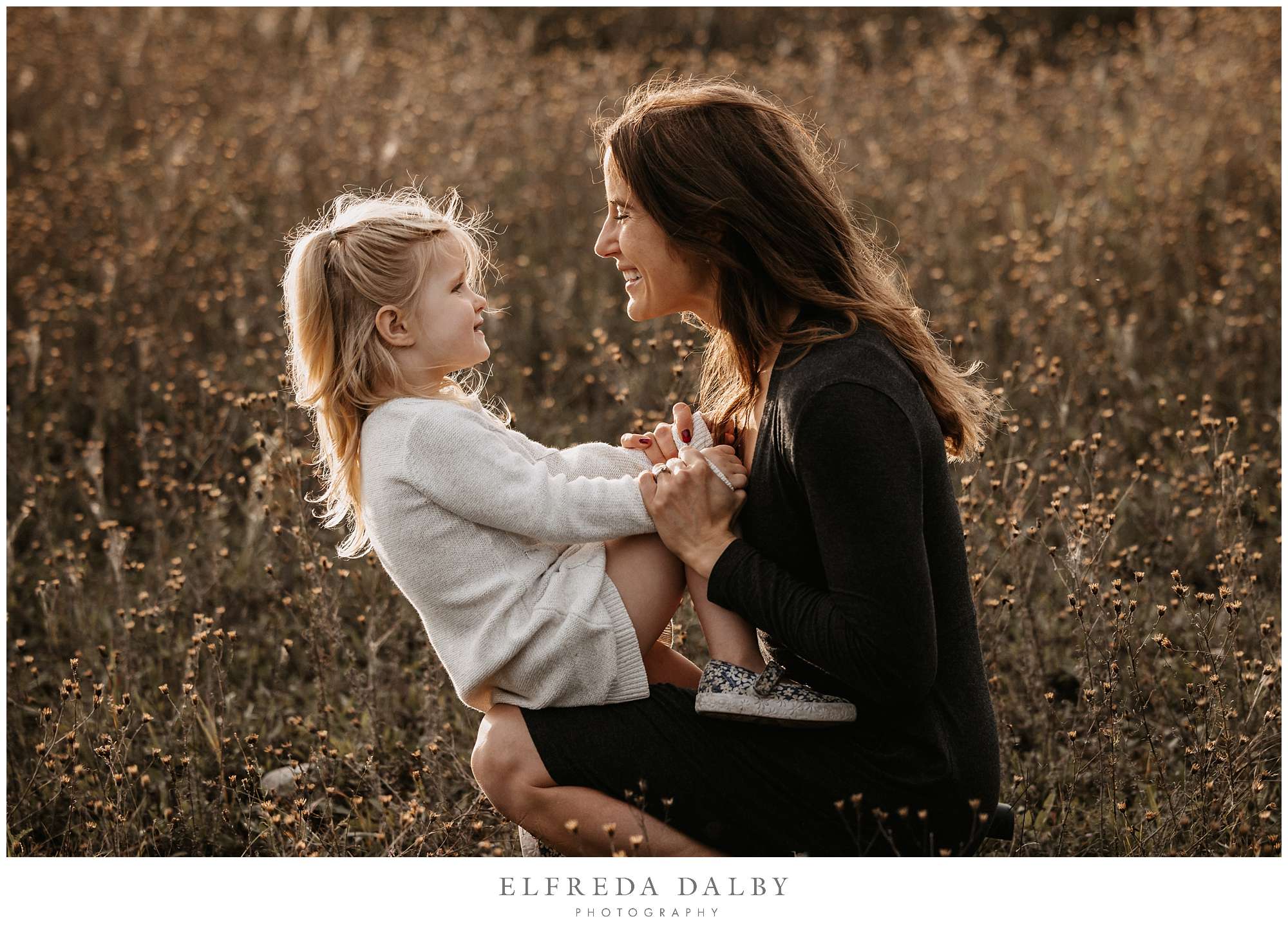 Moment between a little girl and her mom in a field during sunset